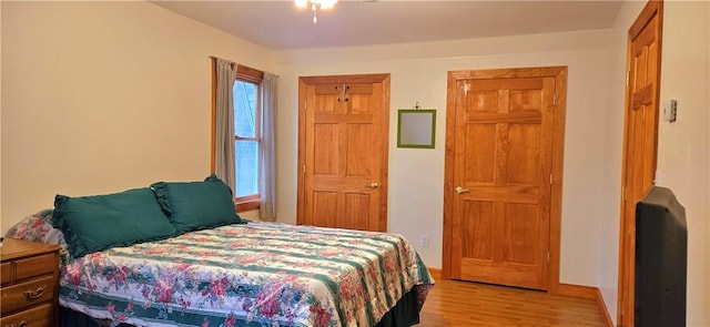 bedroom with baseboards, multiple windows, and light wood finished floors