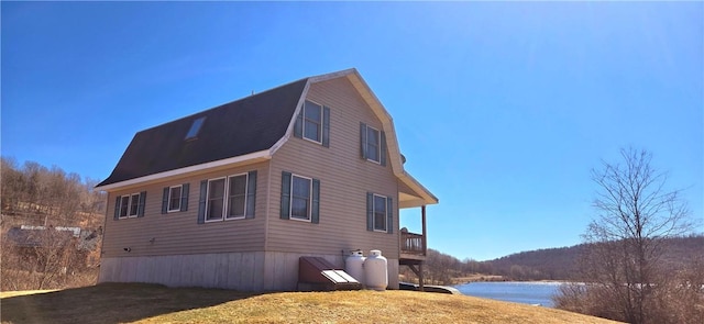 view of side of property featuring a gambrel roof and a water view