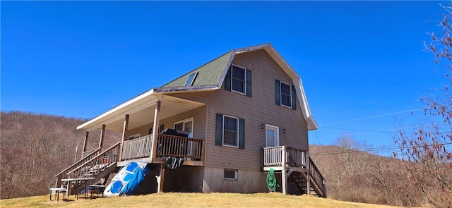 view of side of property with a gambrel roof, stairs, and a lawn