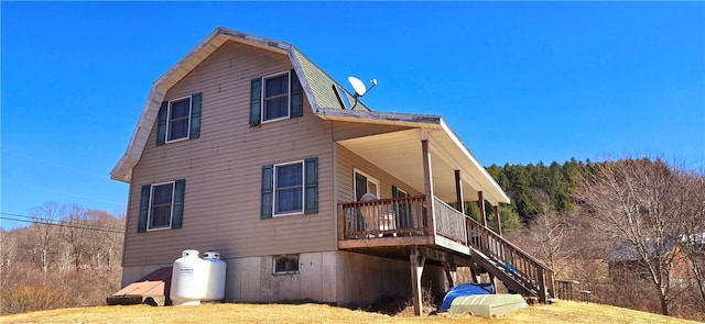 view of home's exterior featuring a gambrel roof, a deck, and stairway
