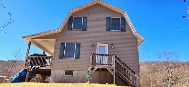 back of house with a gambrel roof, stairway, and a yard