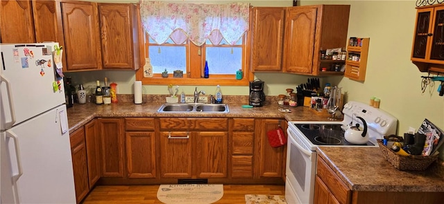 kitchen featuring white appliances, a sink, light wood finished floors, visible vents, and brown cabinets