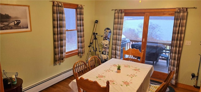 dining space with baseboards, a baseboard heating unit, and wood finished floors