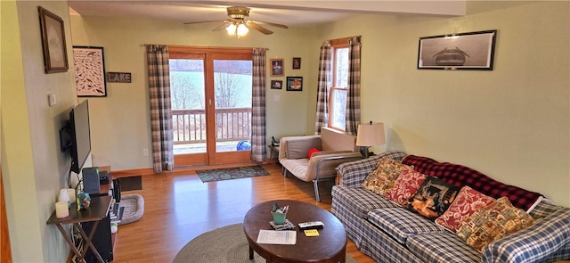 living area with baseboards, ceiling fan, and wood finished floors