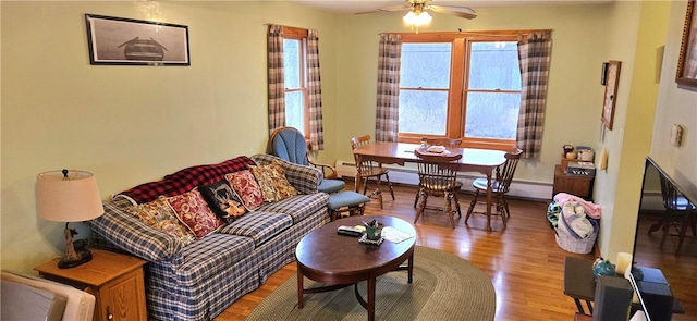 living room with a ceiling fan, baseboards, and wood finished floors