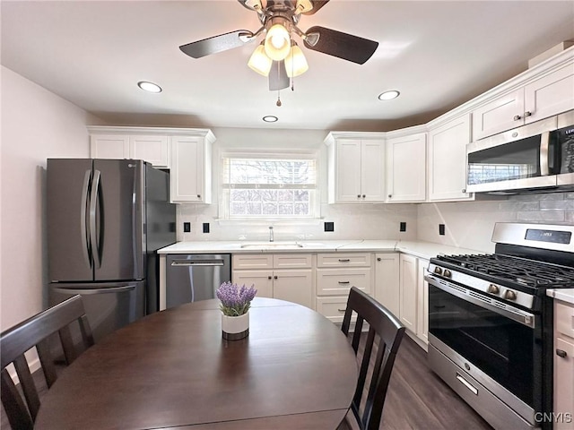 kitchen featuring light countertops, a sink, appliances with stainless steel finishes, white cabinets, and decorative backsplash