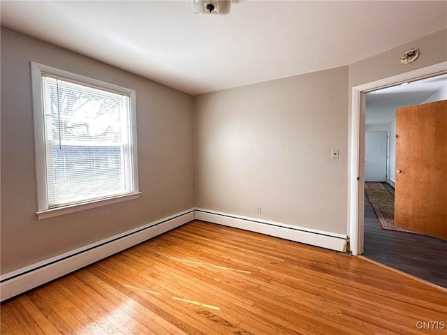 unfurnished room with baseboard heating and light wood-type flooring