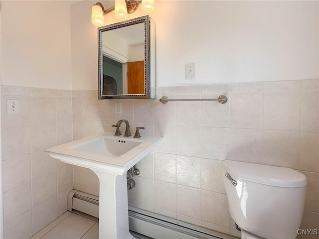half bathroom featuring tile patterned floors, baseboard heating, toilet, and tile walls