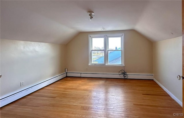 additional living space with light wood-type flooring, lofted ceiling, and a baseboard heating unit