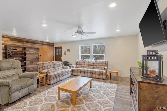 living room featuring an accent wall, wooden walls, wood finished floors, ceiling fan, and recessed lighting