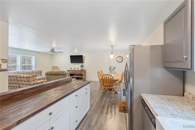 kitchen with butcher block countertops, a ceiling fan, appliances with stainless steel finishes, light wood-style floors, and open floor plan