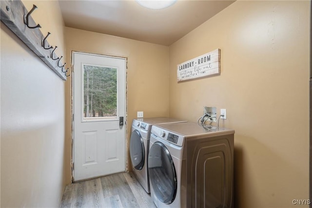 clothes washing area with washing machine and dryer, laundry area, and light wood-style floors