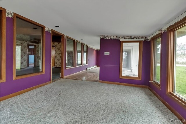 11765 Maple Ridge Rd, Shelby, NY 14103 - carpeted empty room featuring baseboards, a healthy amount of sunlight, and baseboard heating