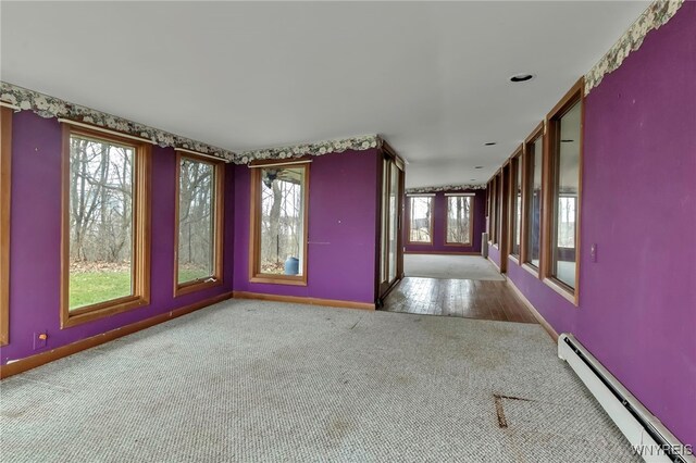 11765 Maple Ridge Rd, Shelby, NY 14103 - carpeted spare room featuring a baseboard radiator, baseboards, and a wealth of natural light
