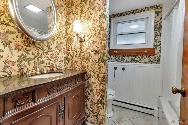 11765 Maple Ridge Rd, Shelby, NY 14103 - bathroom featuring a wainscoted wall, toilet, baseboard heating, tile patterned flooring, and wallpapered walls