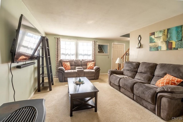carpeted living area with baseboards and stairs
