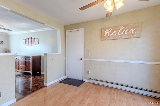 unfurnished room with baseboard heating, baseboards, wood finished floors, and a ceiling fan