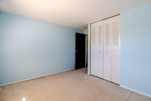 unfurnished bedroom with light colored carpet and a closet
