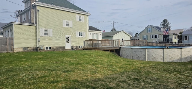rear view of house featuring a fenced in pool, a wooden deck, fence, and a yard