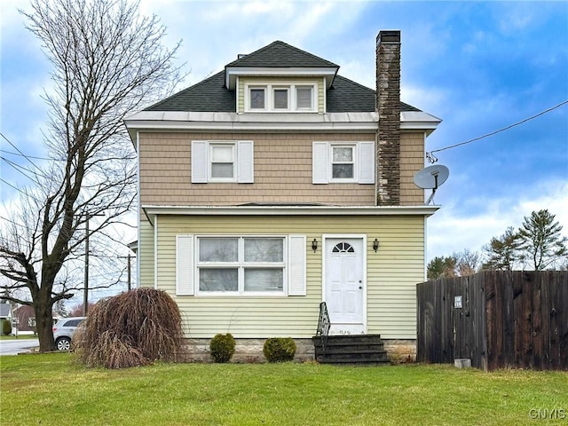 traditional style home with fence, entry steps, a chimney, a front lawn, and roof with shingles