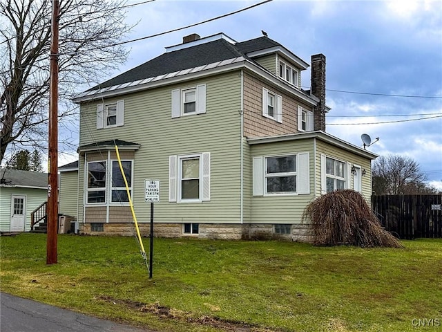exterior space featuring a lawn, a chimney, entry steps, and fence