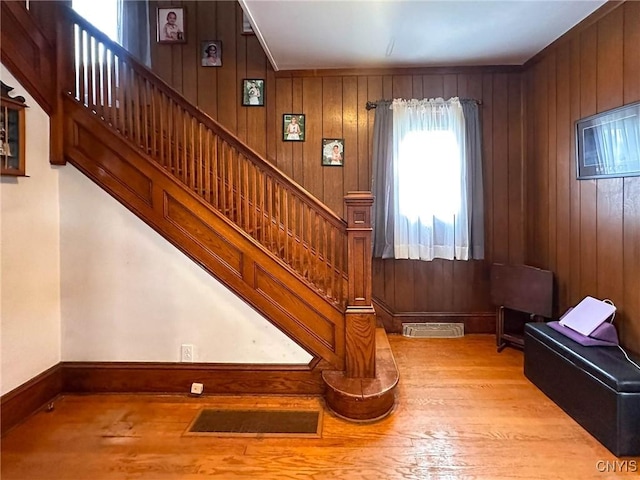 staircase featuring visible vents, wooden walls, and wood finished floors