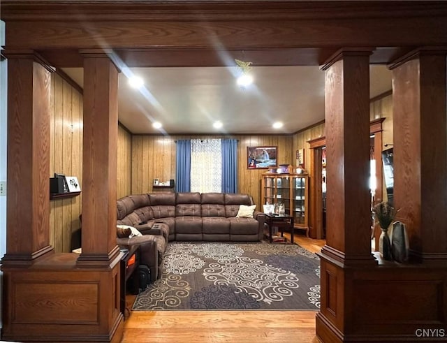 living room with wood finished floors, decorative columns, and wood walls
