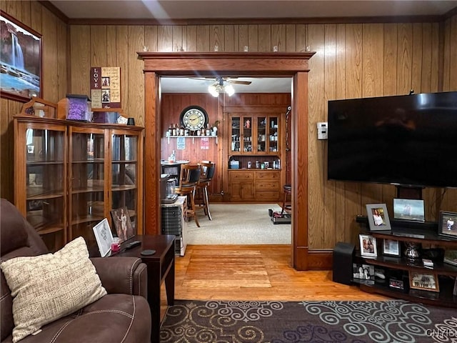 living room featuring a ceiling fan, wooden walls, and wood finished floors