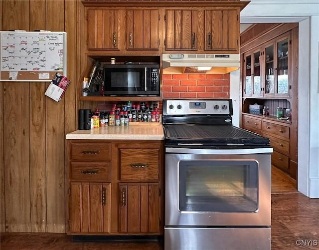 kitchen featuring under cabinet range hood, electric stove, brown cabinetry, and light countertops