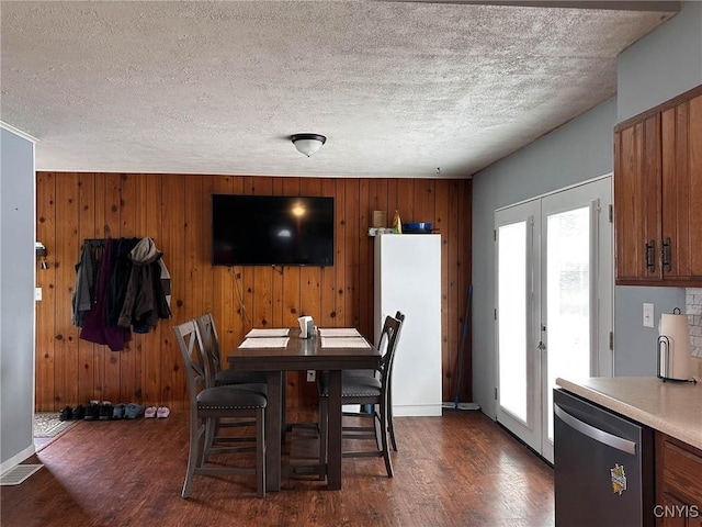 dining space with visible vents, wooden walls, dark wood-type flooring, and a textured ceiling