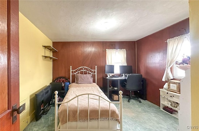 bedroom featuring carpet flooring, a textured ceiling, and wood walls