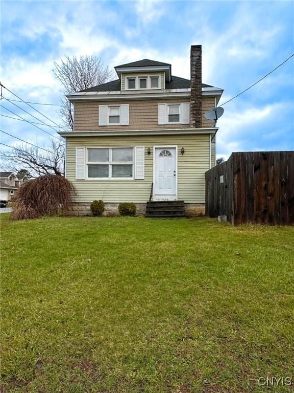 american foursquare style home featuring a front lawn, a chimney, entry steps, and fence