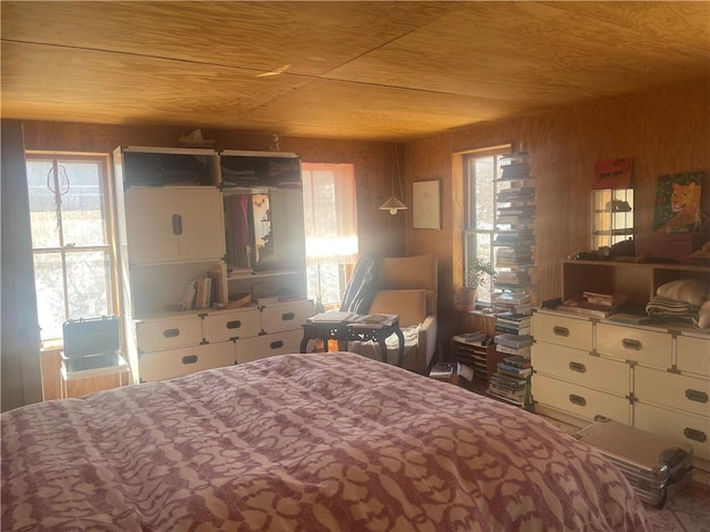 bedroom with wood ceiling, multiple windows, and wooden walls