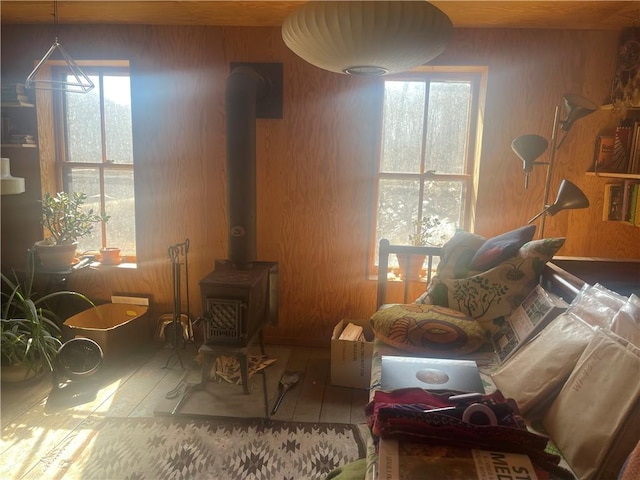 living area with plenty of natural light, wooden walls, and a wood stove
