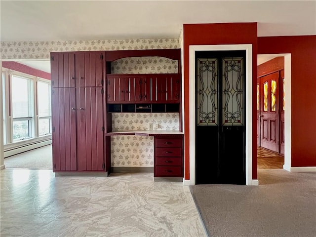 kitchen with baseboards, baseboard heating, reddish brown cabinets, and wallpapered walls