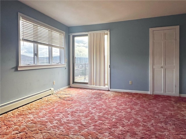 carpeted spare room featuring baseboards and a baseboard heating unit