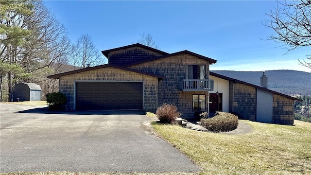 view of front of property featuring a balcony, driveway, a garage, and a front lawn