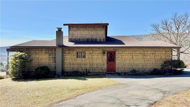 view of front facade featuring a chimney and roof with shingles