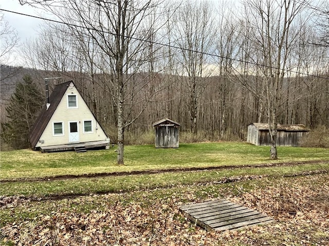 view of yard with a wooded view, an outbuilding, a deck, and a shed