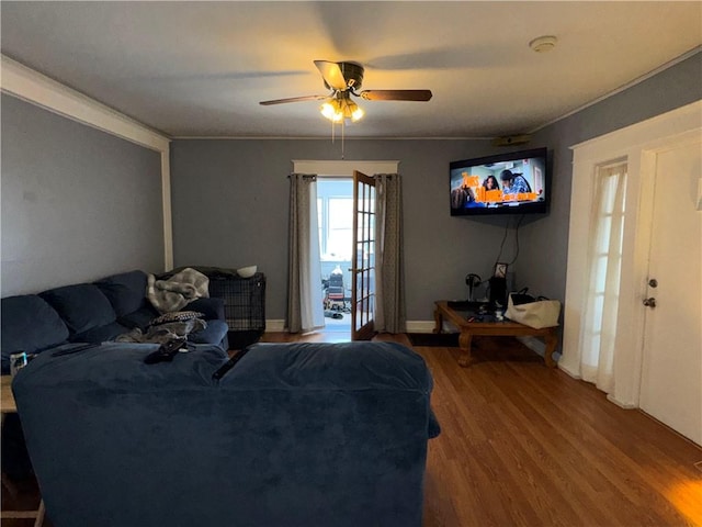 living area featuring baseboards, ornamental molding, wood finished floors, and a ceiling fan