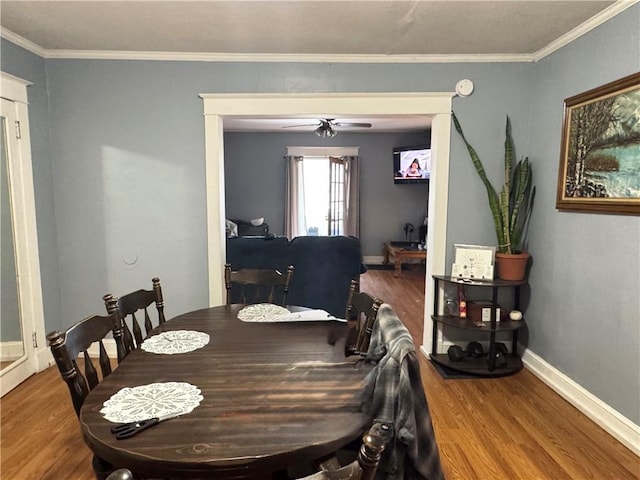 dining space featuring baseboards, wood finished floors, ornamental molding, and a ceiling fan