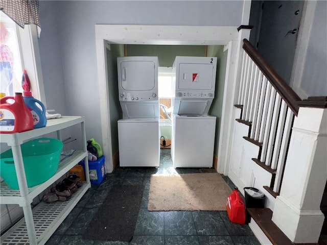 laundry room featuring stone finish floor and stacked washer and clothes dryer