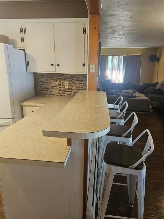 305 State St, Smethport-Borough, PA 16749 - kitchen featuring a breakfast bar area, white cabinets, decorative backsplash, and a peninsula