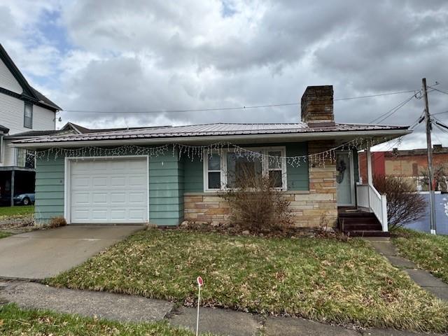 305 State St, Smethport-Borough, PA 16749 - view of front of house featuring stone siding, metal roof, an attached garage, a chimney, and concrete driveway