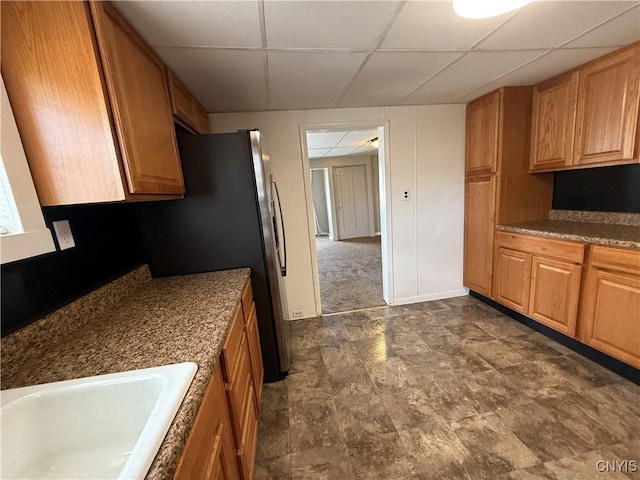 318 Academy St, Watertown-City, NY 13601 - kitchen with a paneled ceiling, a sink, freestanding refrigerator, brown cabinets, and baseboards