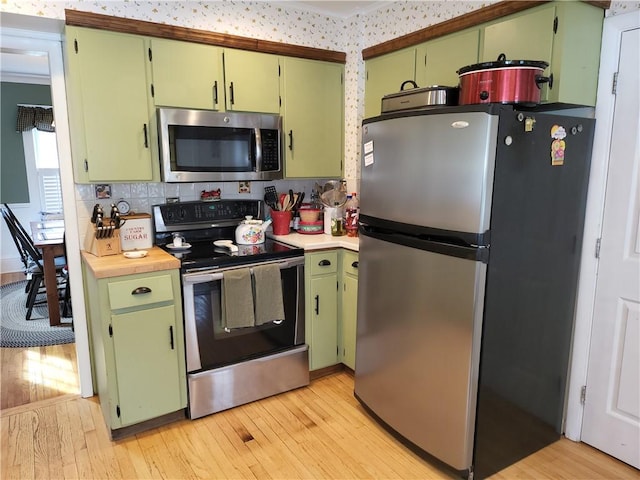114 Country Club Dr, Elmira, NY 14905 - kitchen with light countertops, green cabinetry, stainless steel appliances, decorative backsplash, and light wood-style flooring