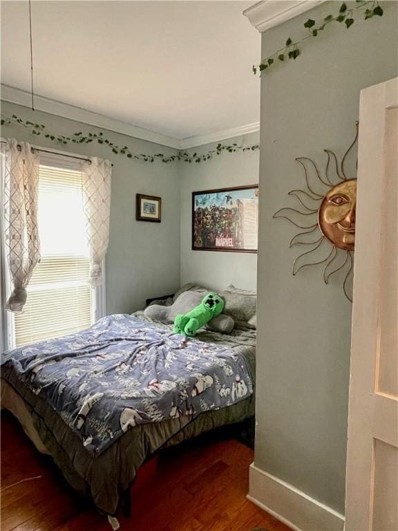 bedroom with crown molding and wood finished floors
