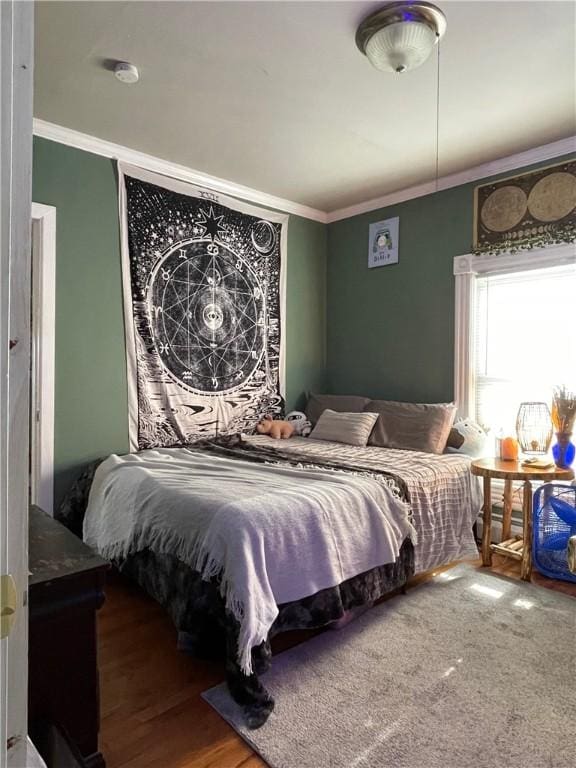 bedroom featuring wood finished floors and ornamental molding