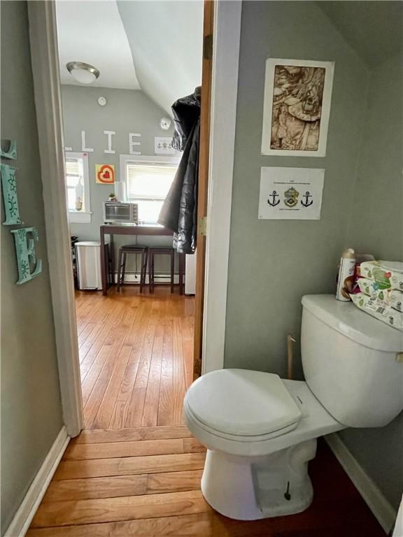 bathroom featuring hardwood / wood-style floors, toilet, baseboards, and vaulted ceiling