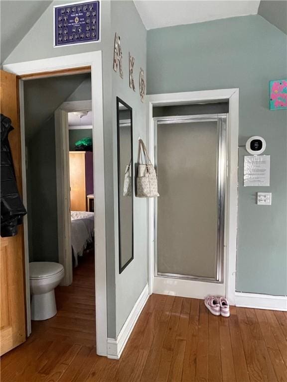 full bathroom with connected bathroom, toilet, vaulted ceiling, and wood finished floors